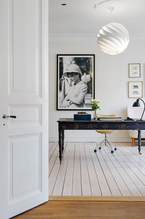 a large black antique desk stands out in an all-white space