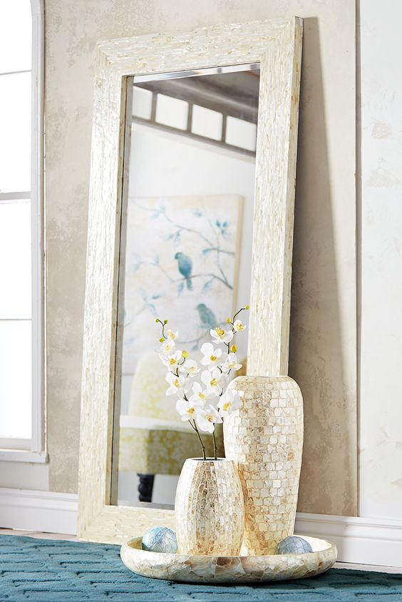 a large mother of pearl mirror and a couple of vases clad with the same material look very feminine and eye-catching