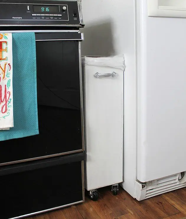 a small and stylish trash can is put between the fridge and the cooker and it's not seen