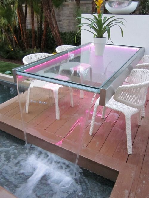 an outdoor glass table with a fountain with neon lights is a spectacular piece 