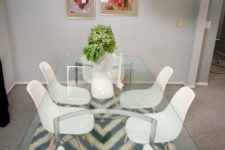 27 a glass top dining table with curved metal legs, modern white chairs and a creative pendant lamp