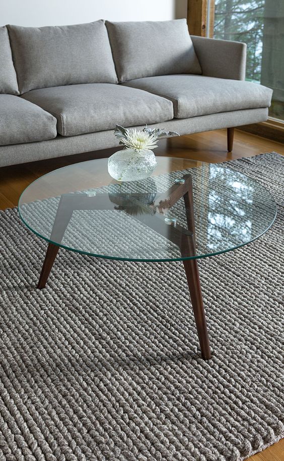 mid-century modern coffee table with dark stained wooden legs and a round glass top