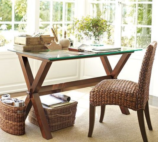 a rustic desk with dark stained wood trestle legs and a glass tabletop