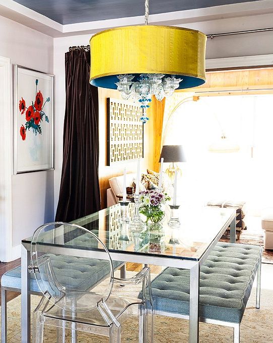 an eye-catchy dining space with a dining table on a metal framing and legs and a glass tabletop and upholstered benches