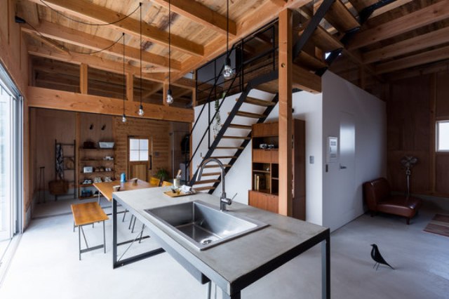 The kitchen and dining spaces are united with the entryway, there's a metal functional space, a wood and black metal dining set and some open shelving