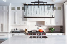 02 The kitchen is white and rather traditional but the accent is made with a unique lighting fixture that blends crystal hangings and industrial details