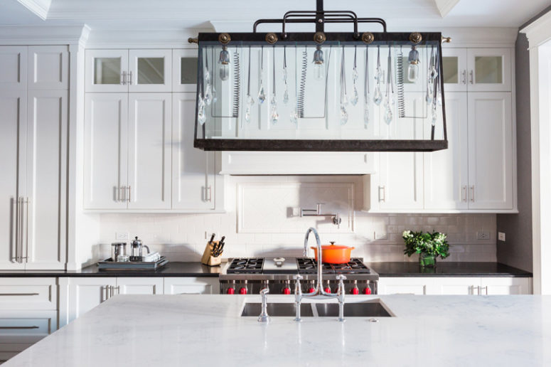 The kitchen is white and rather traditional but the accent is made with a unique lighting fixture that blends crystal hangings and industrial details