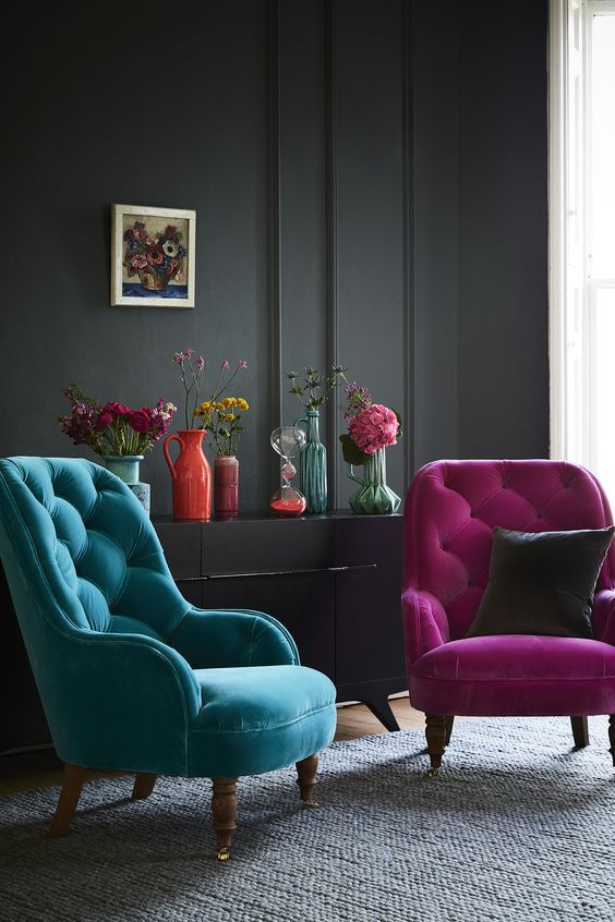 a moody interior is made cheerful with a fuchsia and a turquoise chair and colorful vases