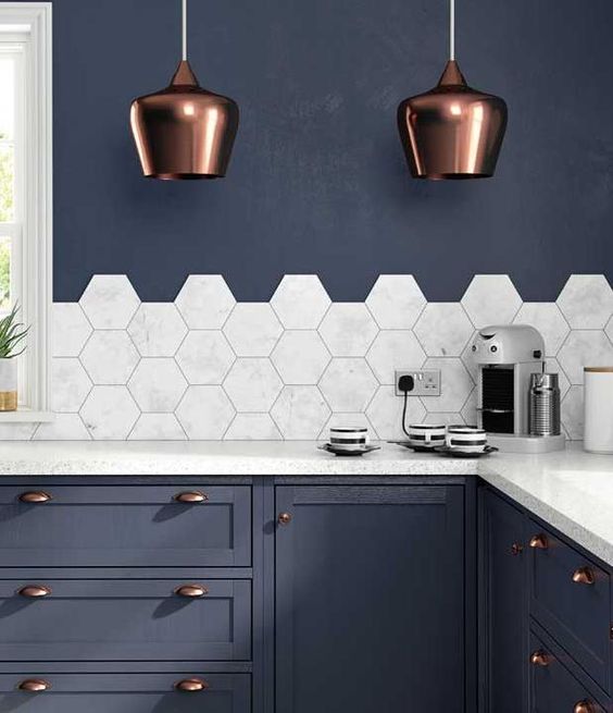 marble hexagon tiles and countertops stand out in this navy grey kithcne with copper accents