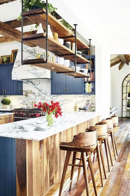the bar counter is decorated in two different ways, blue from the kitchen side and wood from the outer side to fit the decor