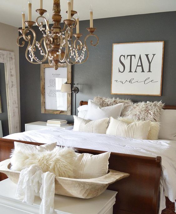 this guest bedroom features a vintage chandelier and a wall sconce for reading in bed