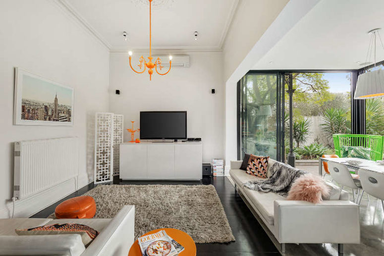 The living space features neutral furniture and decor and some bold orange touches