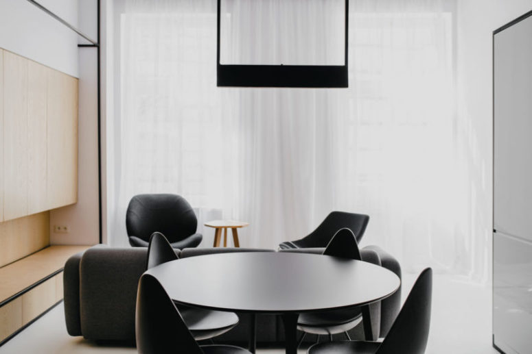 The dining area has a black dining set with a small round table, and wooden sleek cabinets on the left are for storage