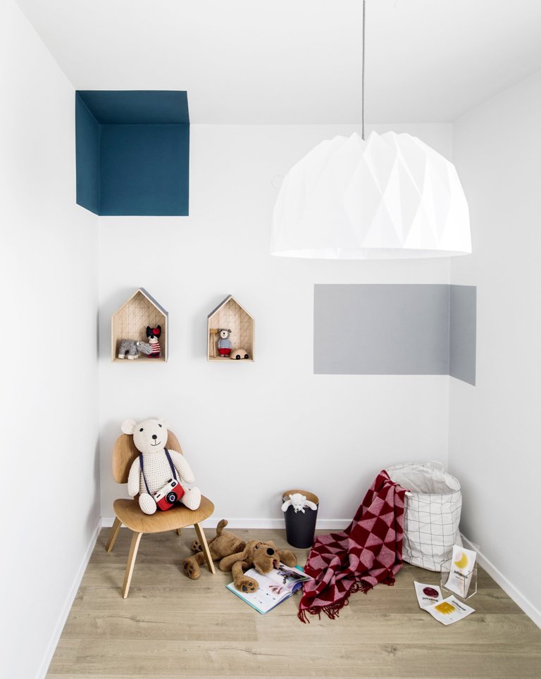 The kid's room features geometric prints, some toys and shouse shaped shelves on the wall