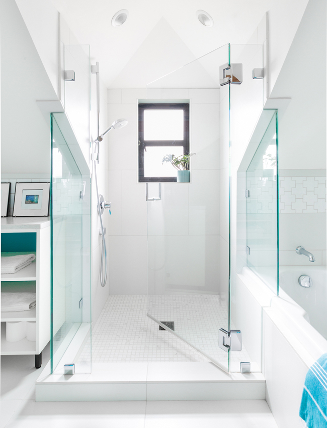 There's a shower with a small window, white tiles and glass doors, which is light-filled