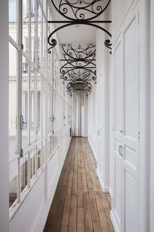 The corridor filled with light through the glazed wall is accentuated with forged vignettes on the ceiling