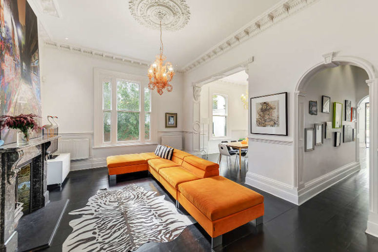 This room features bold orange furniture and an antique fireplace, a bold artpiece catches an eye