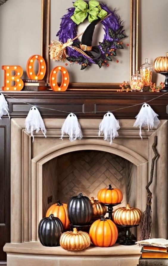 a cheesecloth ghost garland over the fireplace and a pumpkin display inside it