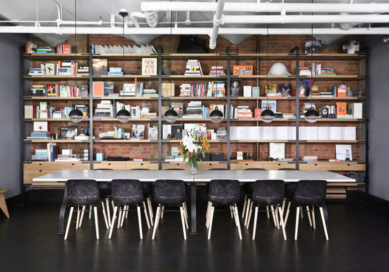 The dining space features large bookshelves that cover the whole wall, a long marble table and black chairs