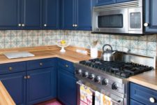 06 a bold blue kitchen with light-colored wooden countertops and a mosaic tile backsplash