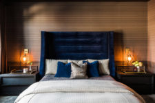 07 The master bedroom is moody and welcoming, with a blue velvet bed and art deco lamps