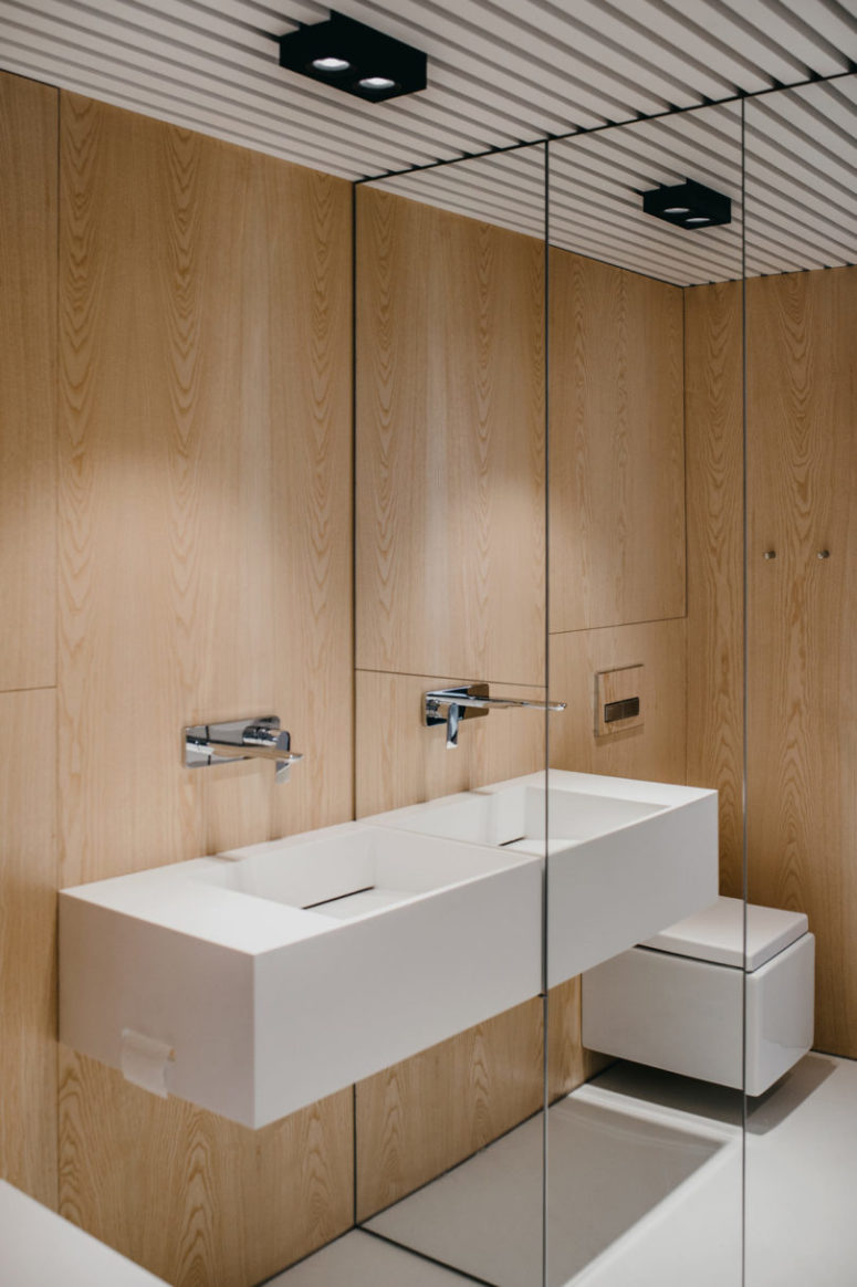The bathroom is clad with light-colored wood, there's a mirror wall to make it look bigger