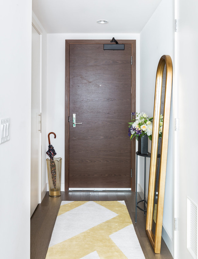 The entryway features a floor mirror, a geo rug and an umbrella stand