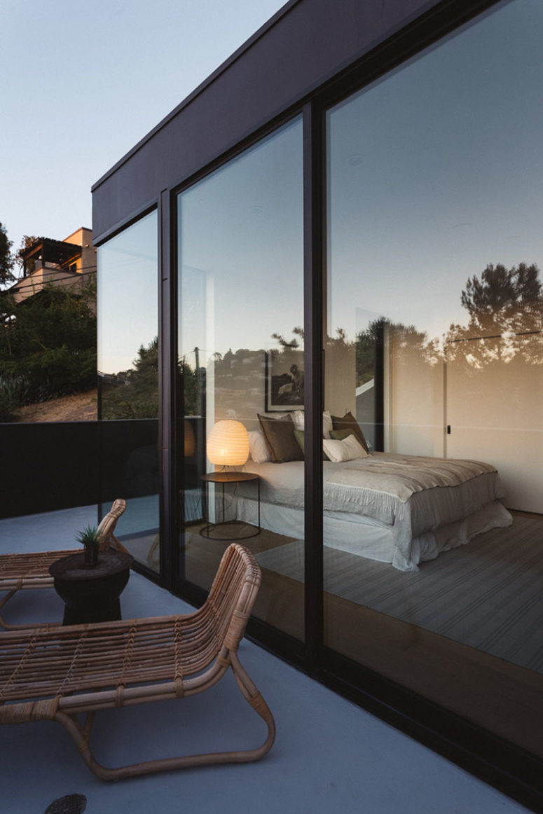 The bedroom has glass walls to connect it to outdoors and fill with light