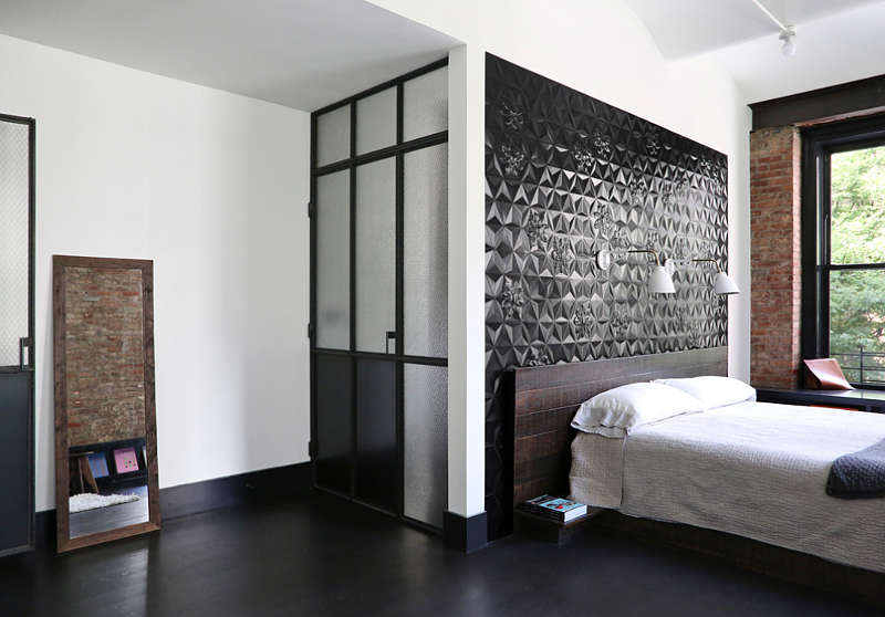 The master bedroom features a black tile statement wall and exposed brick