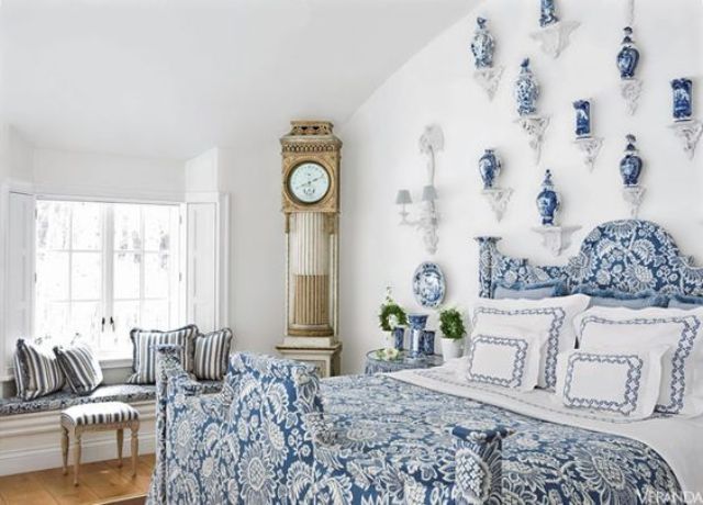 a chic blue bedroom with porcelain vases and a chic vintage clock in the corner