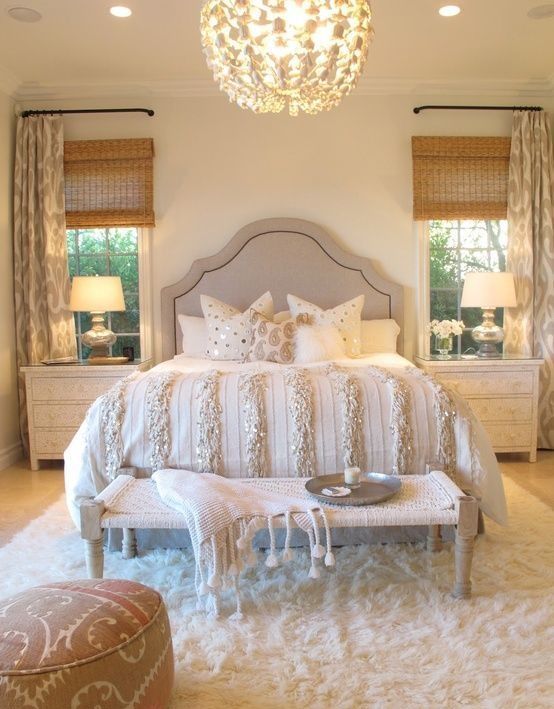 a cozy neutral bedroom with a large chandelier and bedside lamps that fit the look of the room