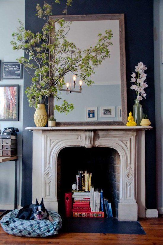 a vintage white stone fireplace is used for book and magazine storage, which is stylish and unexpected