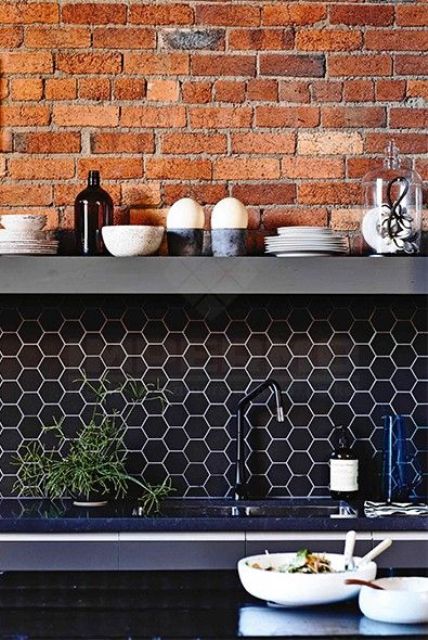 an industrial kitchen with a brick wall, a navy hex tile backsplash and navy countertops