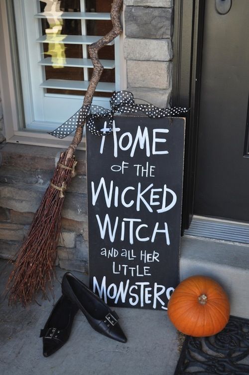 a black and white sign, witch's shoes, a broom and a pumpkin is a nice combo for a porch