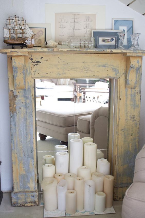 an antique shabby fireplace clad with wood is finished with mirror and some candles