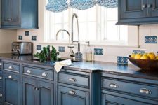 11 blue chalkboard painted cabinets with a vintage design and printed Roman shades