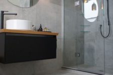 11 concrete-looking matte grey tiles cover the whole bathroom and make it modern and refined