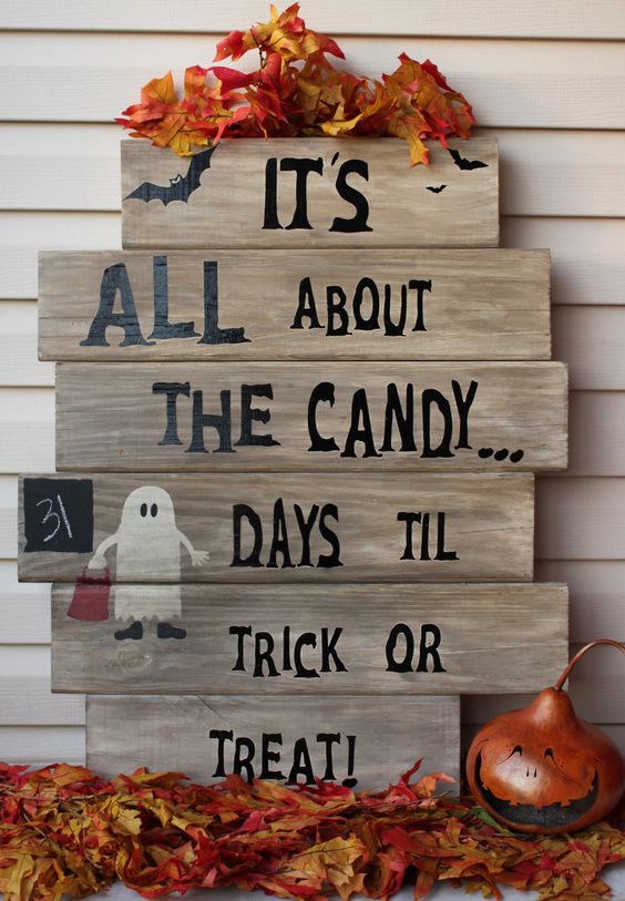 a chic pallet sign with black letters, a painted ghost and faux fall leaves