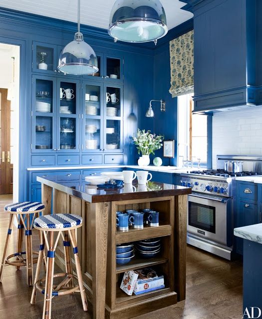bold blue kitchen design with white countertops, stainless steel appliances and a wooden kitchen island