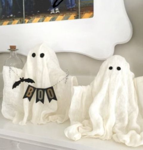 small cheesecloth ghosts with eyes, a banner and a faux bat for mantel decor