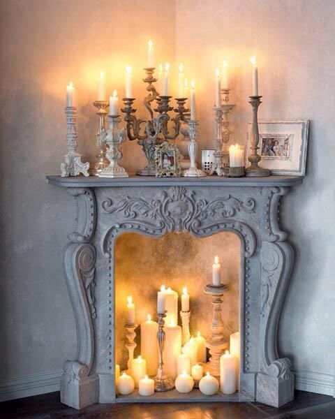 a whitewashed vintage fireplace with lots of candles inside and on the mantel