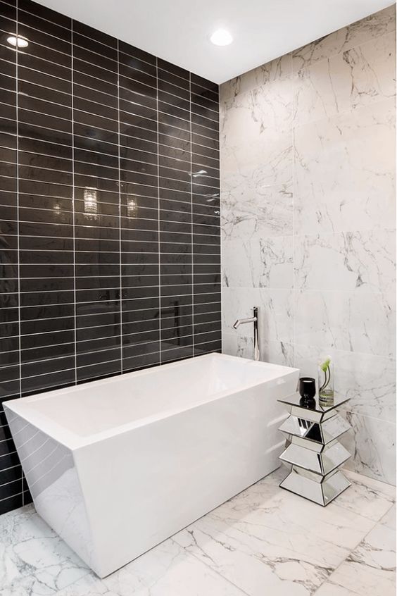 white marble, glossy black tiles and a geometric bathtub make this minimalist space really stand out