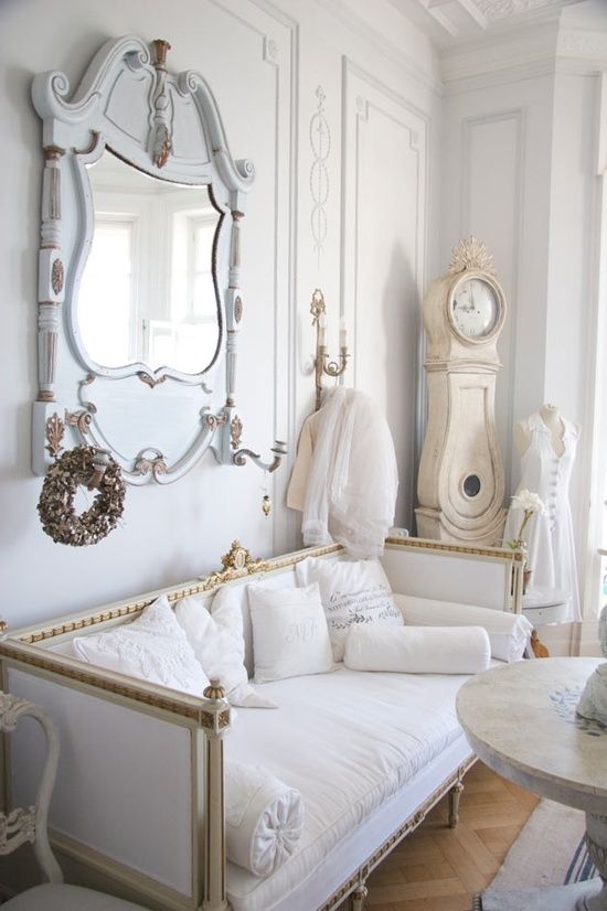 a luxurious interior in white, pastels and gold, with an antique mirror and clock