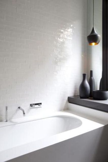 a minimalist bathroom was added a textural touch with glossy white tiles and a matte black pendant lamp