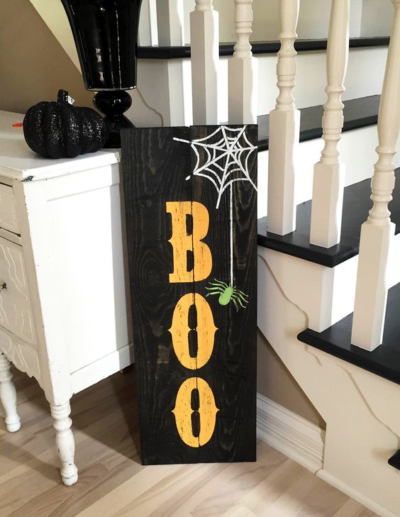 a black pallet sign with BOO letters, a web and a spider is easy to make