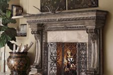 17 a carved casalla wood fireplace is highlighted with a forged metal screen