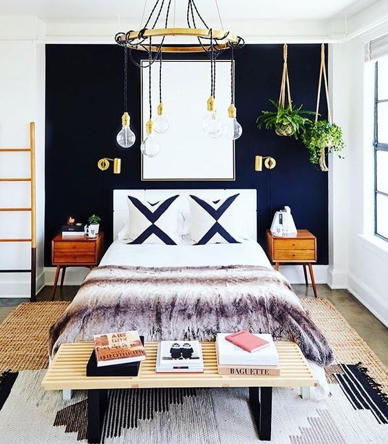 A chic boho inspired bedroom with a navy statement wall and brass touches