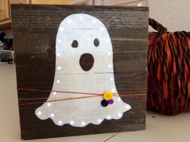 mini pallet sign with a lit up ghost, colorful yarn and buttons