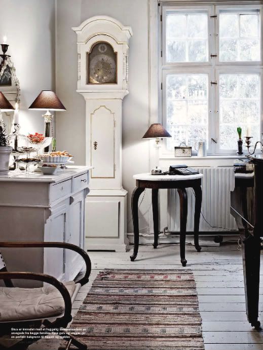 a Scandinavian kitchen with a white and gold grandfather's clock and whitewashed furniture