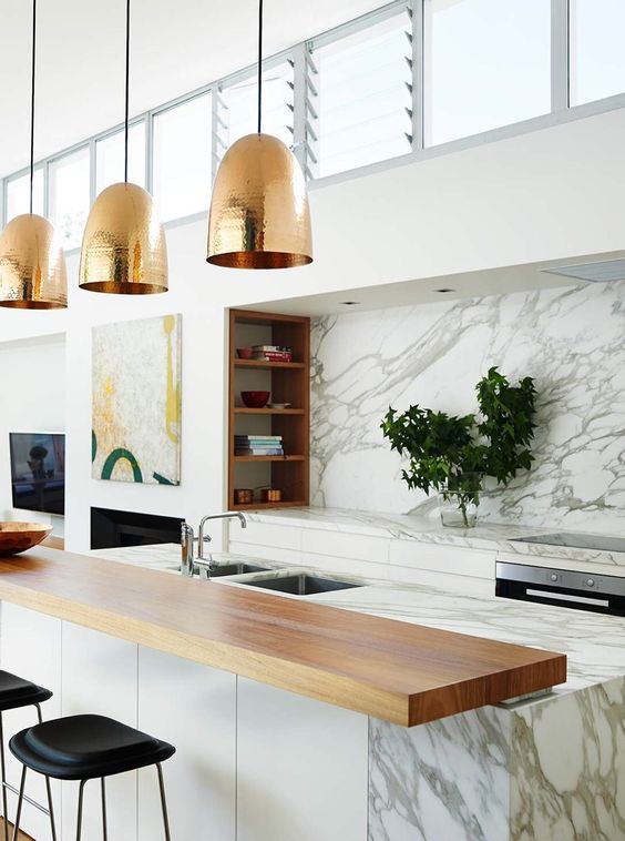 a marble kitchen island is completed with a wooden countertop and a couple of black leather stools